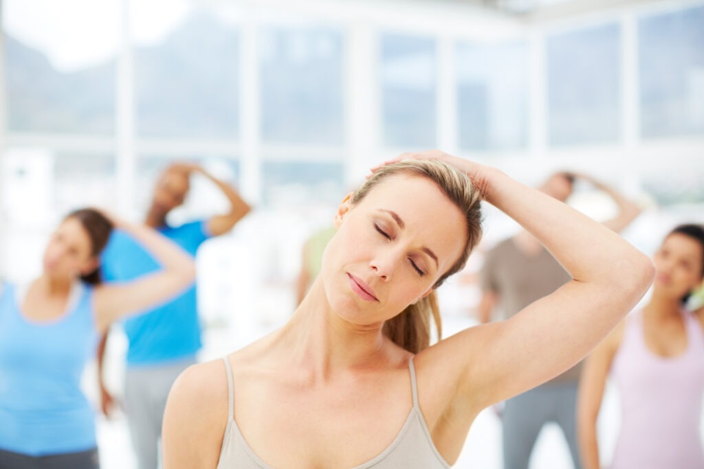 Attractive yoga instructor leading her class in a stretch with her eyes shut